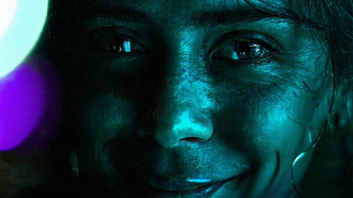 Close-up of a person's expressive face in a video call, with subtle emotion hinting at a poker tell
